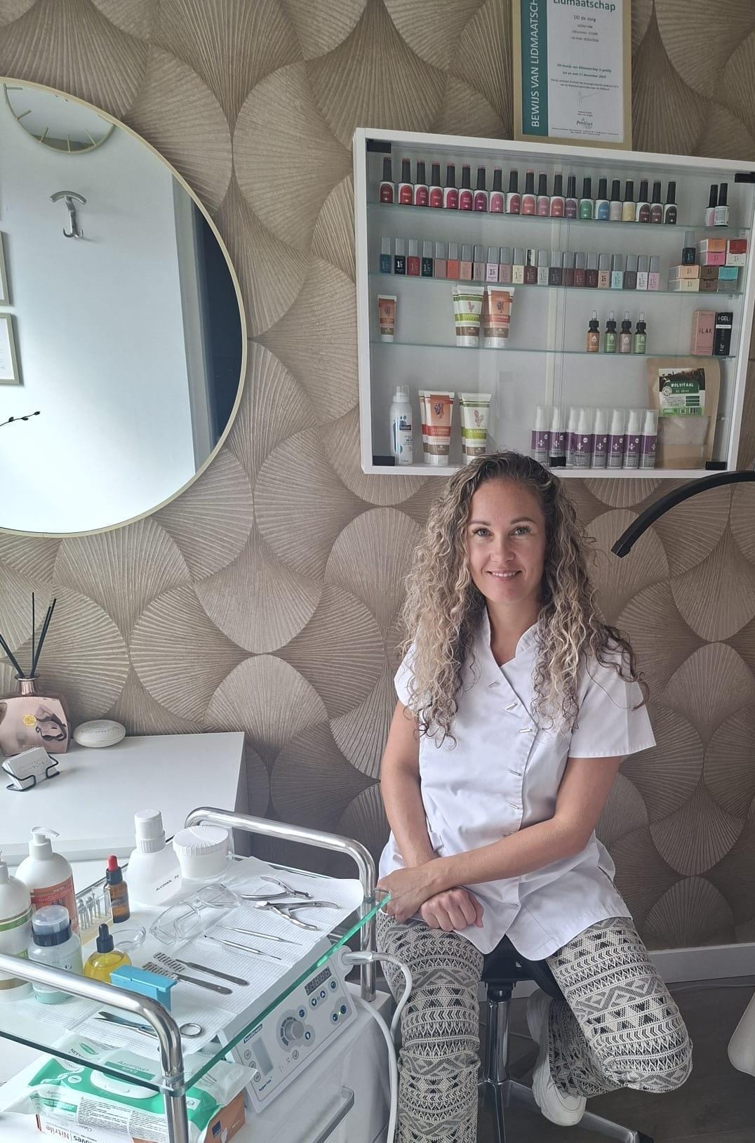 Danielle in haar salon, naast de behandeltrolley en de productenplank