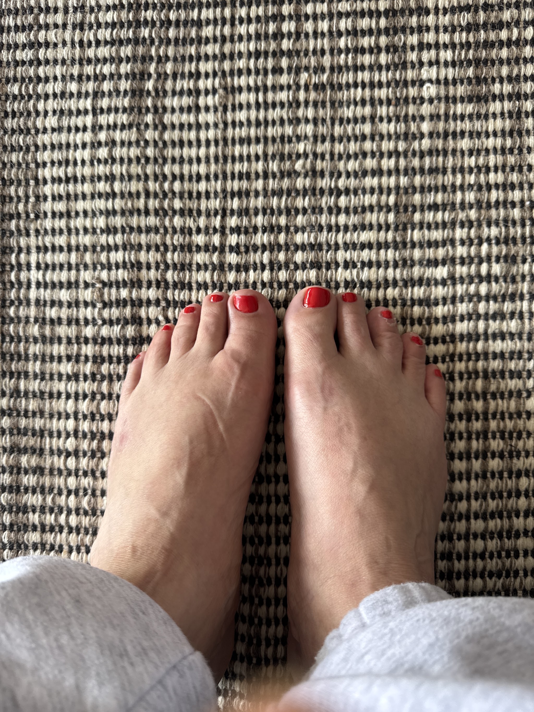 Voeten met rode nagellak op een jute vloerkleed na een pedicure