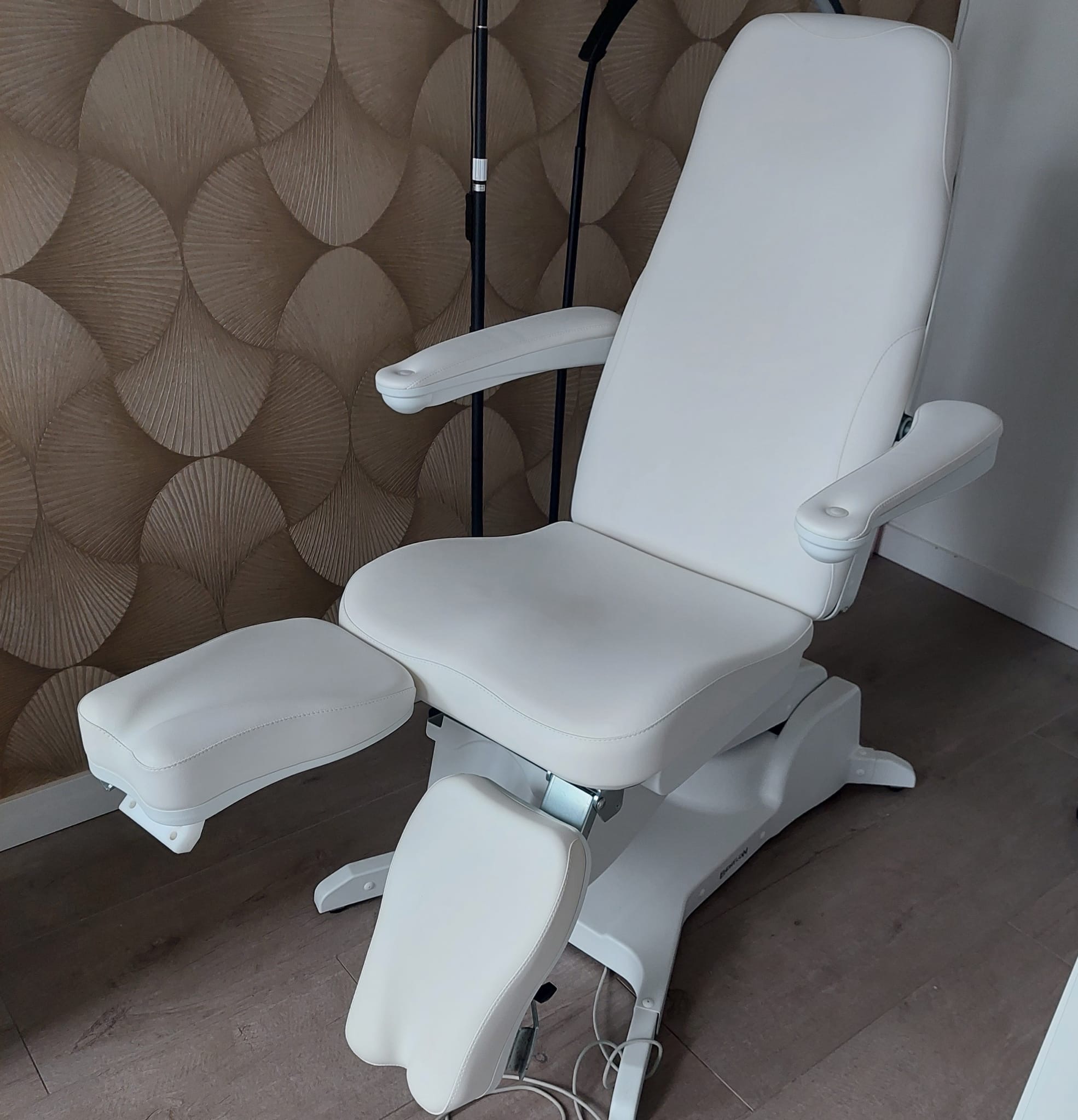 Witte pedicurestoel tegen de wand met gouden patroon